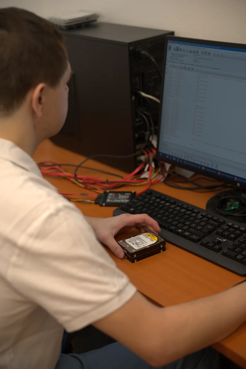 Odborník ITHOPE drží 3,5-palcový HDD pred diagnostickým počítačom pri vstupnej analýze.